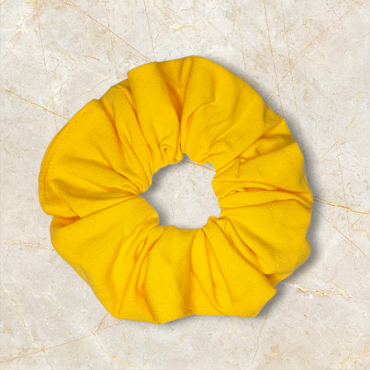 Keltainen puuvillainen hiusdonitsi tasaisella vaalealla taustalla, pehmeä scrunchie arkeen ja kampauksiin. Damaski.