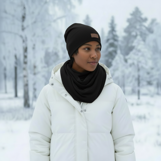 Musta merinovillainen kaulahuivi mallin kaulassa talvisessa metsämaisemassa. Damaski, kotimainen.
